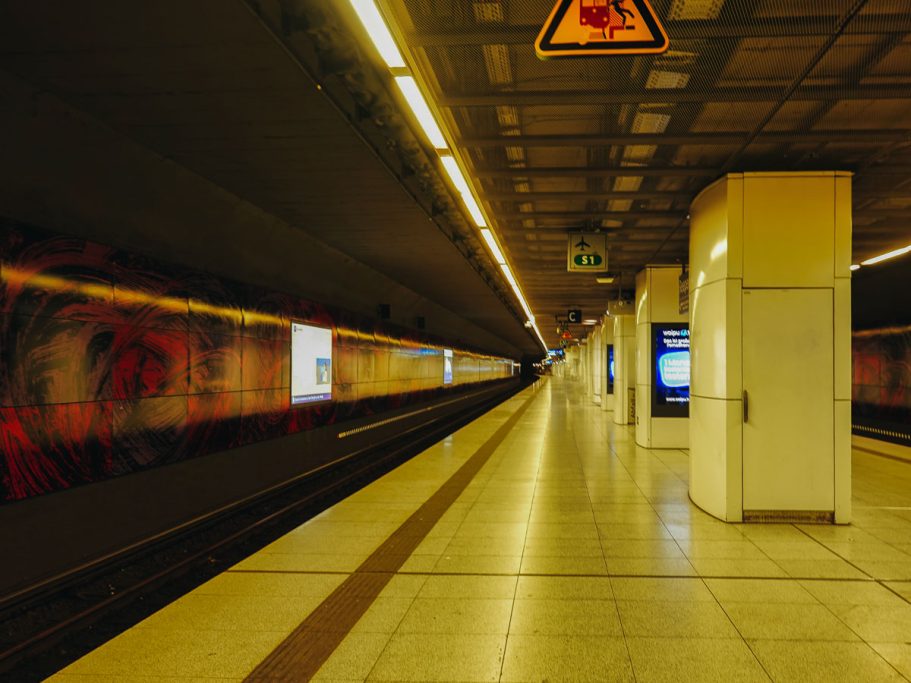 U-Bahn-Station mit leeren Gleisen und moderner Architektur, schwaches Licht.