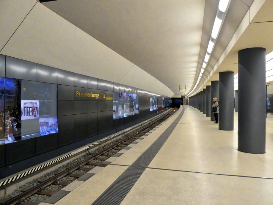 U-Bahn-Station mit langen Bahnsteig und sichtbaren Gleisen, beleuchtet und modern gestaltet.