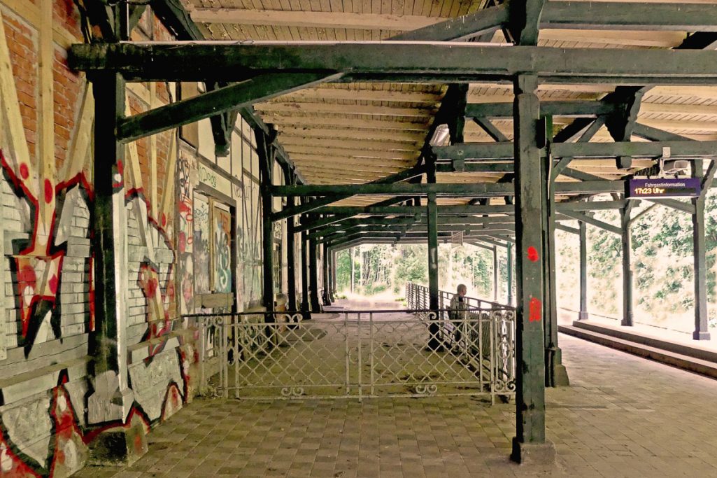 Verlassene Bahnhofsplattform mit Graffiti und Stahlträgern im Hintergrund.