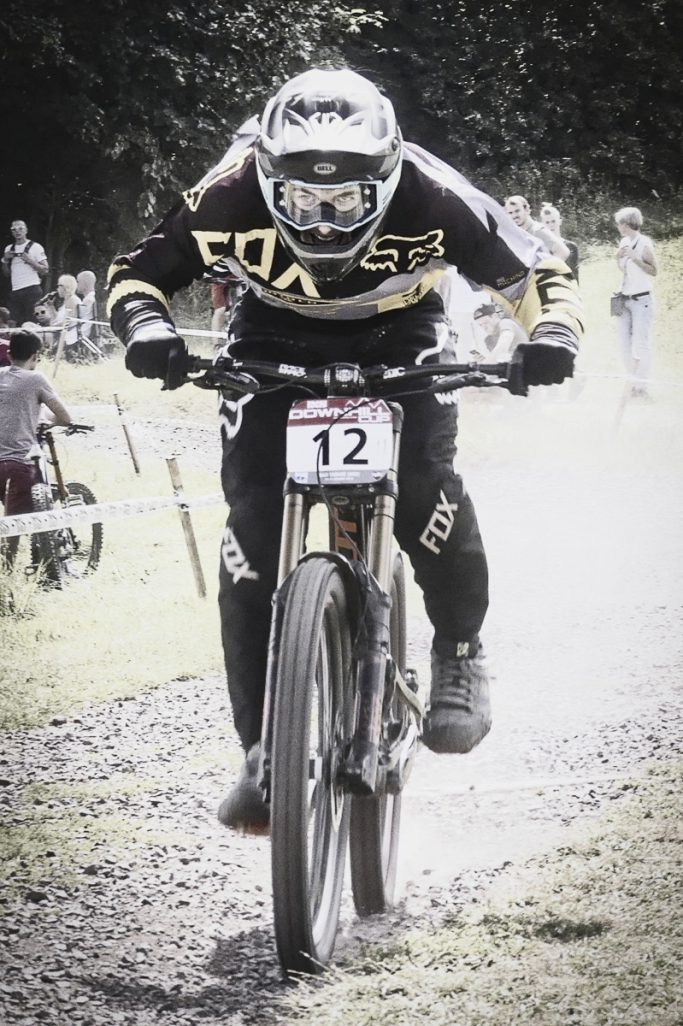 Ein Mountainbiker fährt mit hoher Geschwindigkeit über einen unebenen Weg.